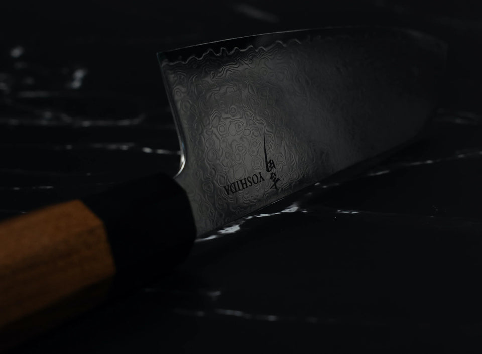 Détail de la lame acier Damas VG-10 du couteau santoku Yoshida avec gravure de la marque et manche en bois