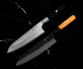 Set Yoshida : Santoku 18 cm AUS-10 à manche noir et Gyuto 20 cm VG-10 à manche en olivier, côte à côte