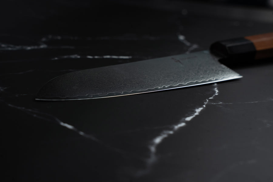 Lame en acier Damas VG-10 d'un couteau japonais de cuisine Yoshida sur fond de marbre noir