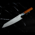 Couteau Kiritsuke japonais Yoshida posé sur marbre noir, finition acier 440C