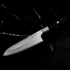 Profil du Santoku 18 cm AUS-10 vendu avec le Gyuto pakkawood : lame Damas et manche en bois noir, sur marbre